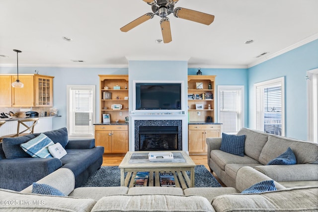 living room featuring a premium fireplace, crown molding, ceiling fan, and light hardwood / wood-style floors