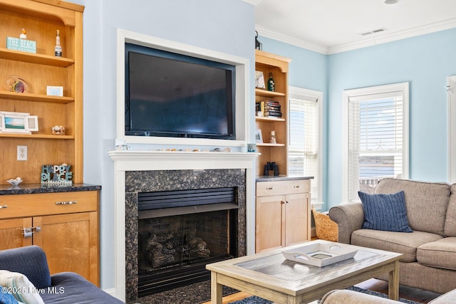 living room featuring built in shelves, ornamental molding, and a premium fireplace