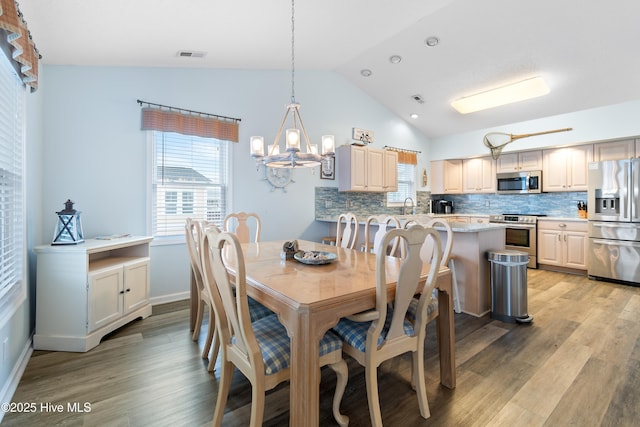 dining area featuring vaulted ceiling, visible vents, and light wood-style floors