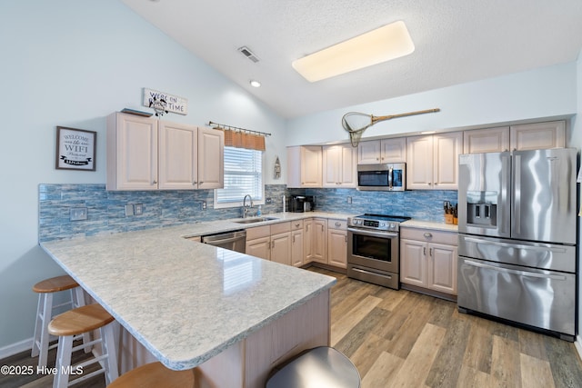 kitchen with a breakfast bar area, stainless steel appliances, light countertops, visible vents, and a sink