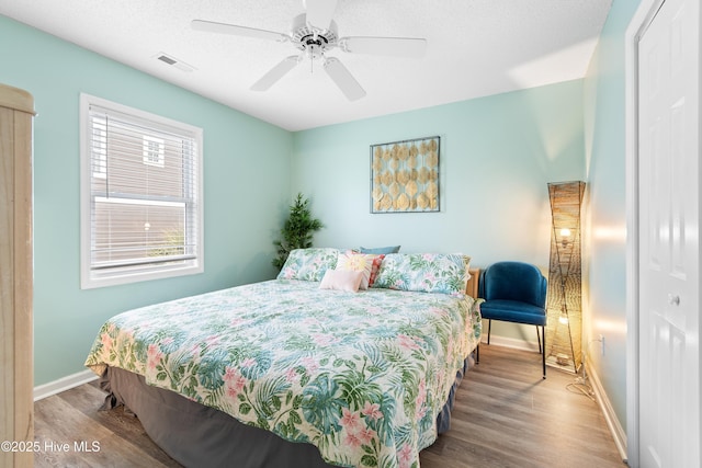 bedroom with baseboards, visible vents, and wood finished floors