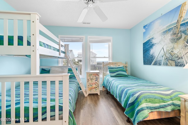 bedroom featuring a textured ceiling, wood finished floors, visible vents, and a ceiling fan