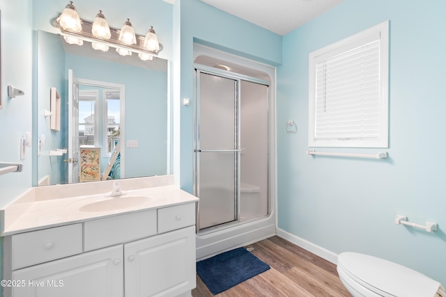 full bath with toilet, a stall shower, wood finished floors, and vanity