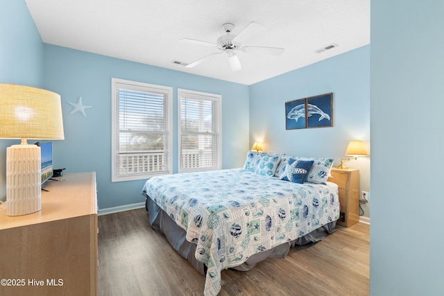 bedroom with baseboards, visible vents, and wood finished floors