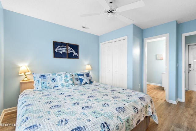 bedroom featuring a closet, visible vents, ceiling fan, wood finished floors, and baseboards