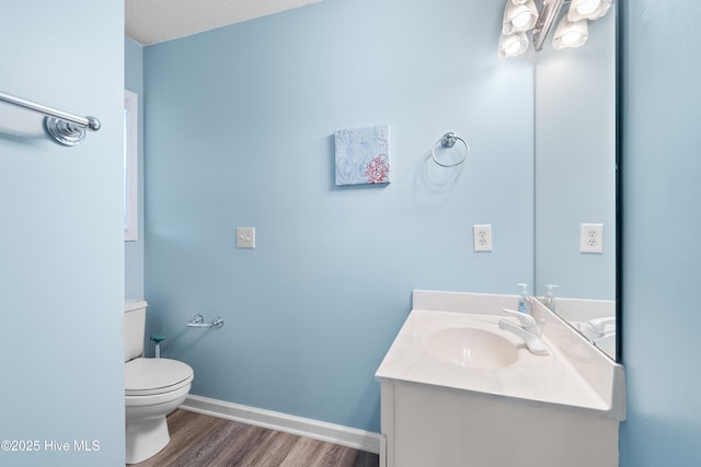 half bathroom featuring vanity, wood finished floors, toilet, and baseboards