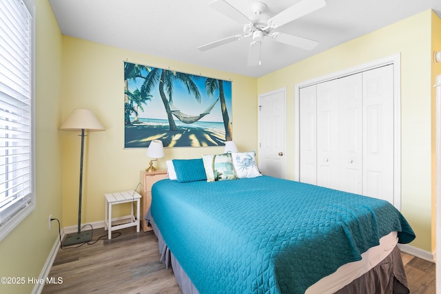 bedroom featuring a ceiling fan, a closet, baseboards, and wood finished floors