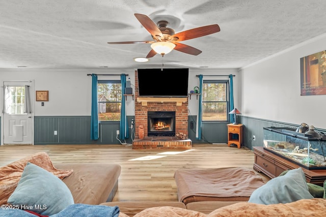 living room featuring crown molding, a brick fireplace, a textured ceiling, and light hardwood / wood-style floors