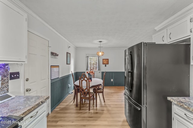 kitchen featuring decorative light fixtures, white cabinets, crown molding, black fridge, and a textured ceiling