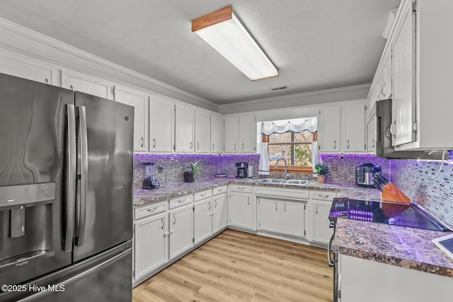 kitchen with sink, crown molding, stainless steel fridge, and white cabinets