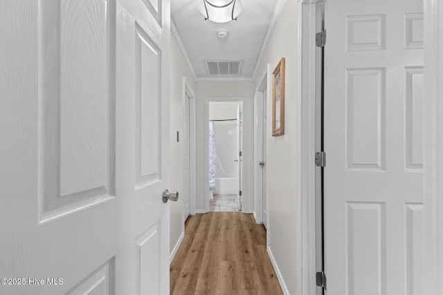 hall with crown molding, a textured ceiling, and light wood-type flooring