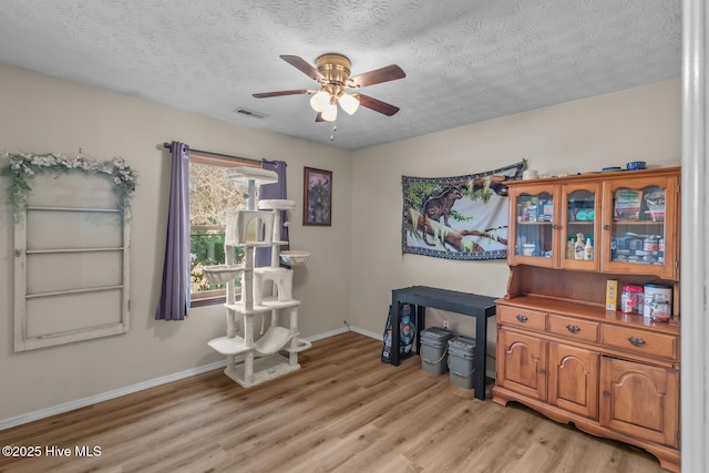 misc room featuring ceiling fan, light wood-type flooring, and a textured ceiling