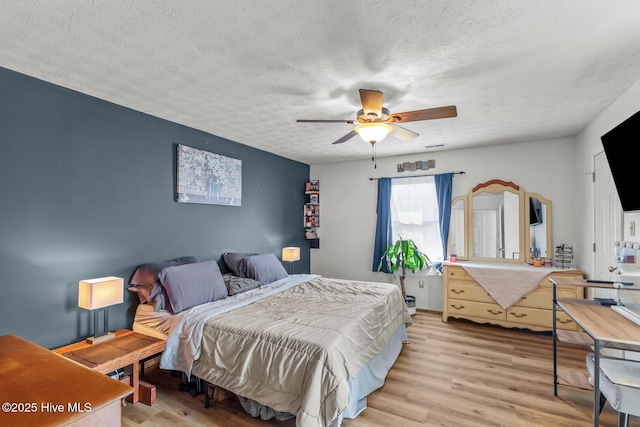 bedroom with a textured ceiling, light hardwood / wood-style floors, and ceiling fan