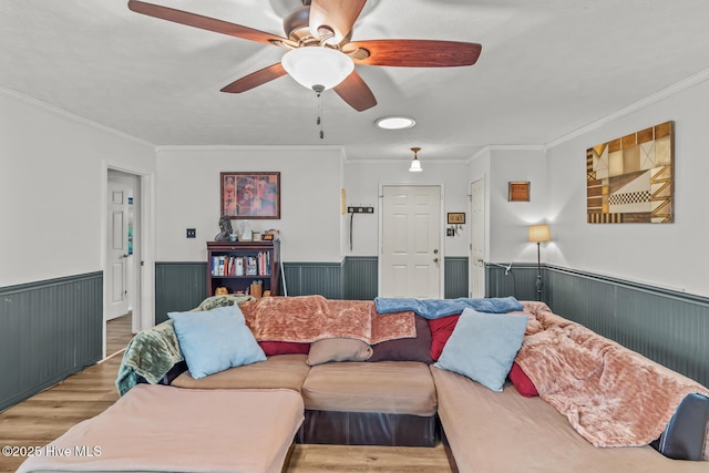 living room featuring ceiling fan, ornamental molding, and wood-type flooring