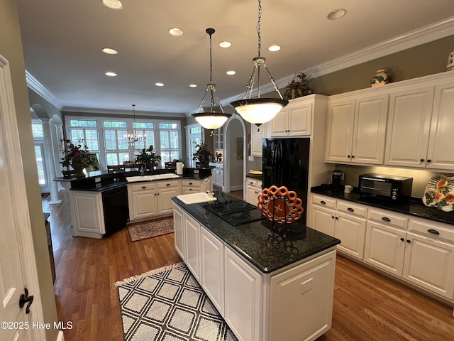 kitchen with black appliances, decorative light fixtures, a kitchen island, and white cabinets