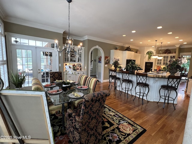 dining room with crown molding, a notable chandelier, hardwood / wood-style flooring, and french doors