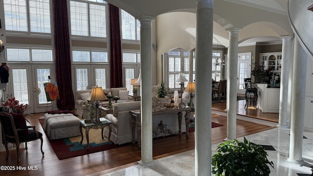 living room featuring a towering ceiling, ornamental molding, and ornate columns