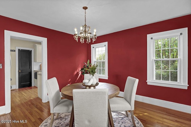 dining space with an inviting chandelier, baseboards, and wood finished floors