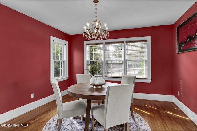 dining space with a notable chandelier, baseboards, and wood finished floors