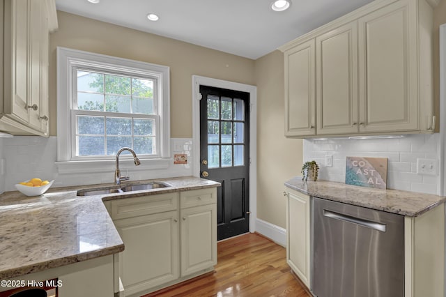 kitchen featuring stainless steel dishwasher, plenty of natural light, a sink, and light stone countertops