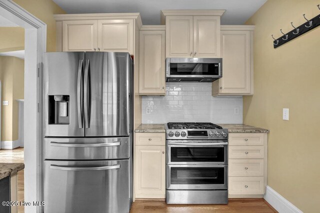 2817 Park Ave, Wilmington, NC 28403 - kitchen featuring appliances with stainless steel finishes, cream cabinets, tasteful backsplash, light stone countertops, and light wood finished floors