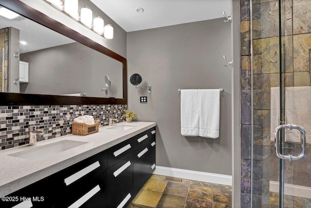 full bathroom featuring a shower stall, a sink, backsplash, and baseboards