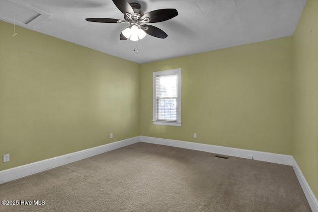 carpeted spare room with ceiling fan, visible vents, attic access, and baseboards