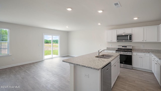 kitchen featuring sink, appliances with stainless steel finishes, a kitchen island with sink, white cabinetry, and light wood-type flooring