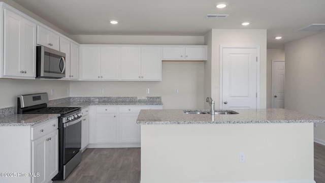 kitchen featuring white cabinetry, dark wood-type flooring, stainless steel appliances, and a center island with sink