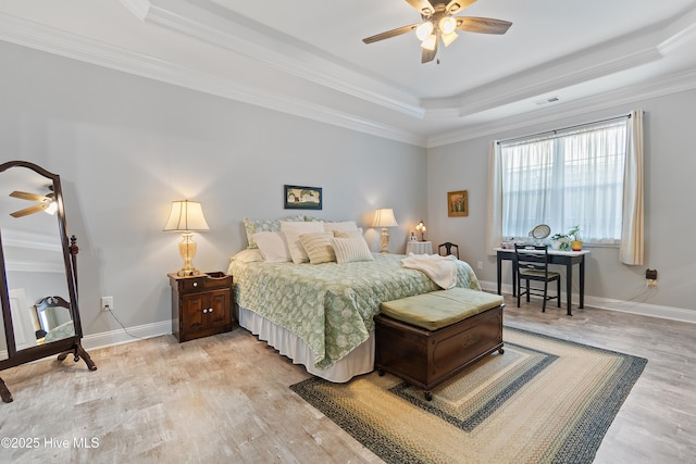 bedroom with a tray ceiling, crown molding, baseboards, and light wood-type flooring