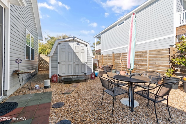 view of patio / terrace with fence, an outbuilding, outdoor dining space, and a shed