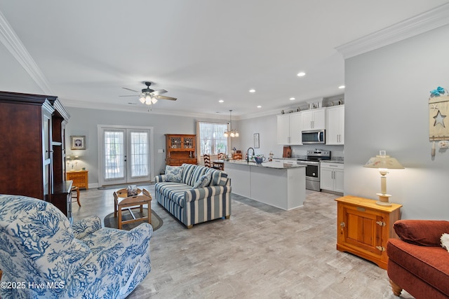 living area with ceiling fan with notable chandelier, crown molding, recessed lighting, and baseboards