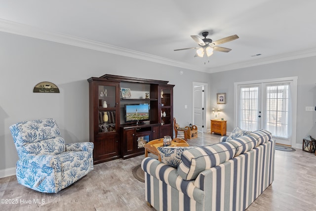 living room featuring french doors, baseboards, light wood finished floors, and ornamental molding