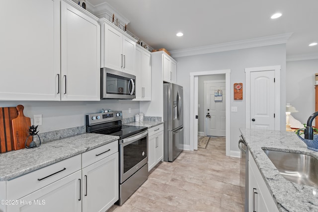 kitchen with white cabinetry, crown molding, appliances with stainless steel finishes, and a sink