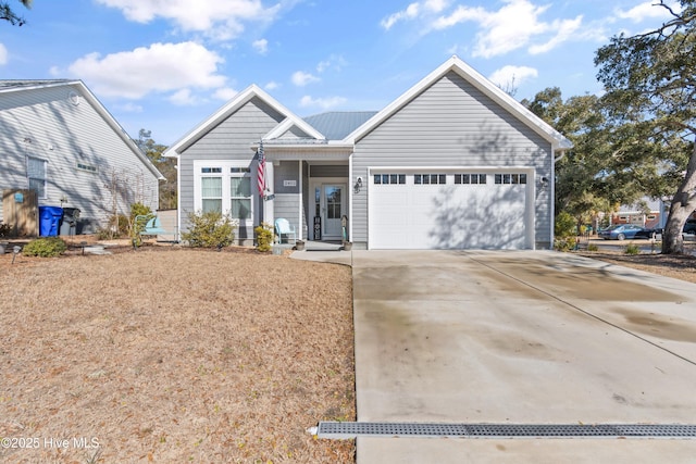 ranch-style house featuring metal roof, driveway, and an attached garage