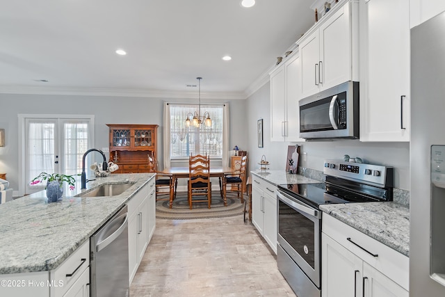 kitchen with light wood finished floors, crown molding, appliances with stainless steel finishes, white cabinetry, and a sink