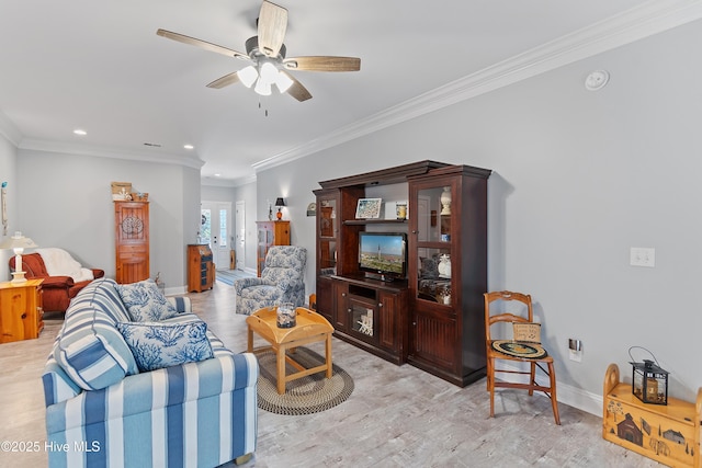 living area featuring light wood-type flooring, baseboards, ceiling fan, and ornamental molding