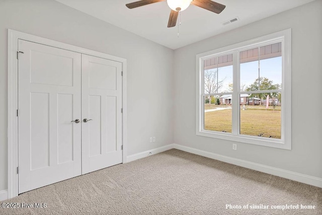 unfurnished bedroom featuring carpet floors, a closet, visible vents, a ceiling fan, and baseboards