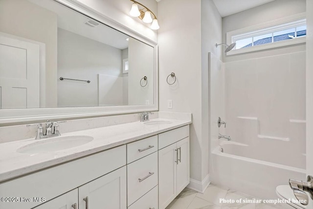 bathroom featuring double vanity, marble finish floor, shower / bathing tub combination, and a sink