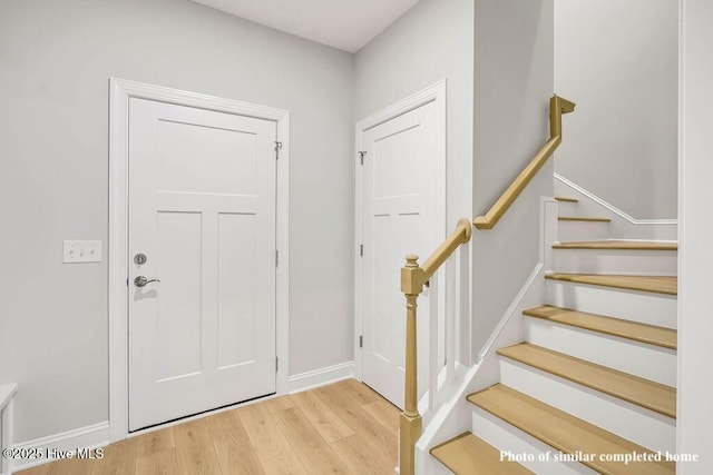 entryway with stairs, baseboards, and wood finished floors