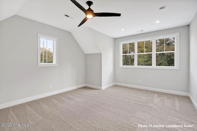 additional living space with light colored carpet, lofted ceiling, visible vents, and baseboards