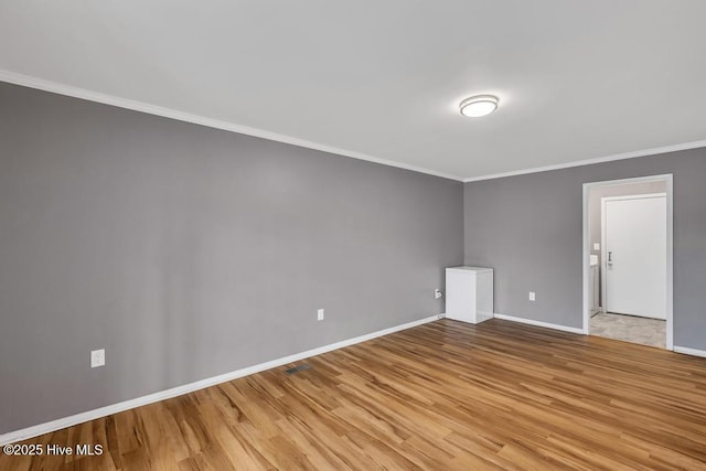 spare room featuring crown molding and light hardwood / wood-style flooring