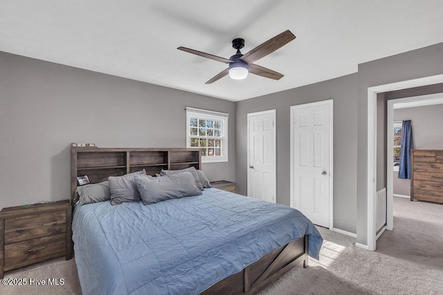 bedroom featuring two closets, light colored carpet, and ceiling fan