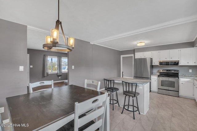 kitchen featuring stainless steel appliances, a kitchen island, white cabinets, and decorative light fixtures