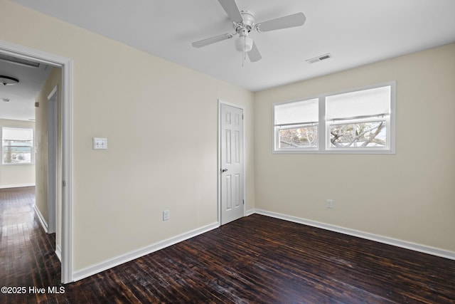 empty room with dark wood-type flooring, ceiling fan, and a wealth of natural light