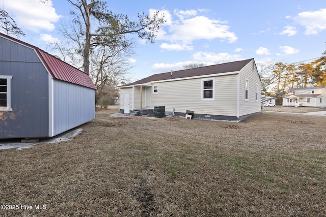 rear view of property featuring an outbuilding, a lawn, and central air condition unit