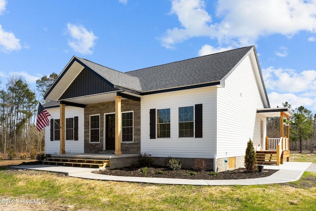 view of front of house featuring a porch, board and batten siding, a front yard, and a shingled roof