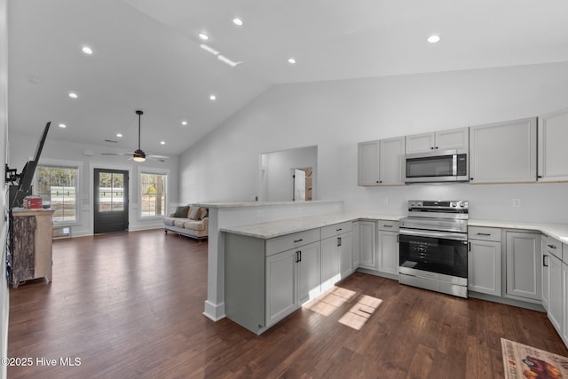 kitchen with dark wood-type flooring, appliances with stainless steel finishes, gray cabinets, and kitchen peninsula