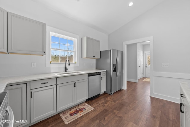 kitchen featuring lofted ceiling, sink, dark wood-type flooring, gray cabinets, and stainless steel appliances