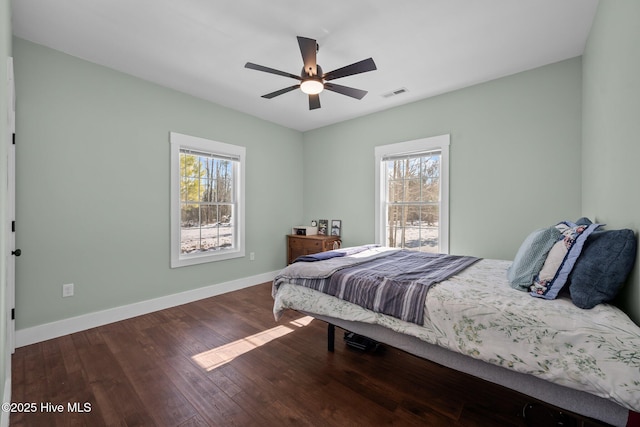 bedroom with multiple windows, dark wood-type flooring, and ceiling fan